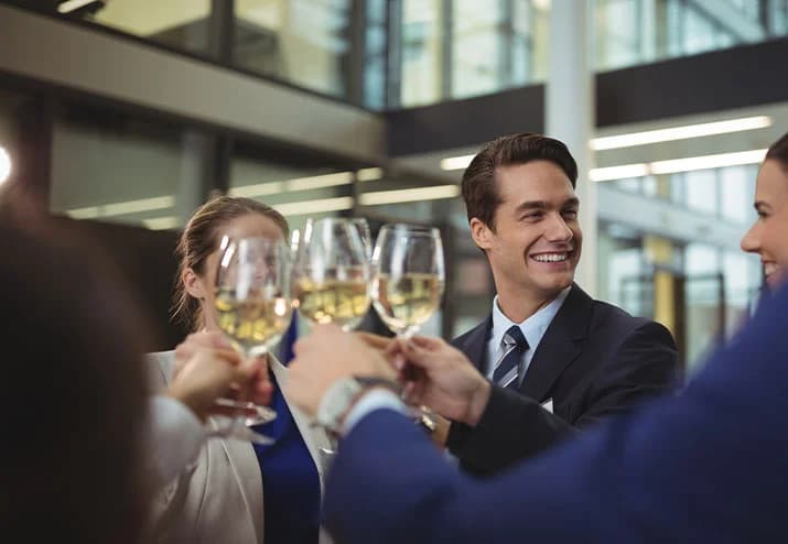 Kolleginnen und Kollegen stoßen bei einer Firmenfeier mit Sekt an